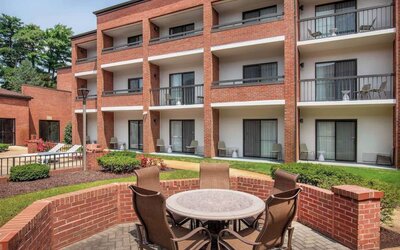 The hotel patio is close to the rooms, and has a circular table surrounded by a quintet of chairs.
