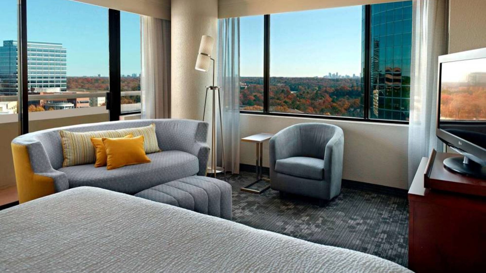 Sonesta Select Atlanta Cumberland Galleria double bed guest room, featuring sofa, chair, windows, and TV.