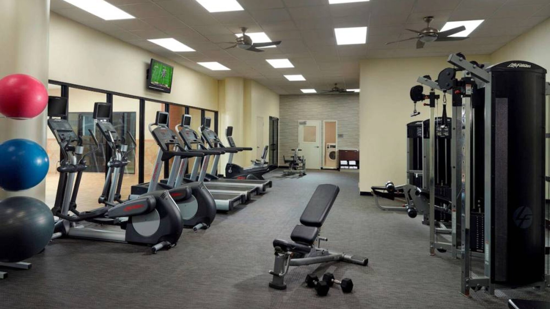 The hotel fitness center has an assortment of exercise machines, plus free weights and benches, and a wall-mounted TV.