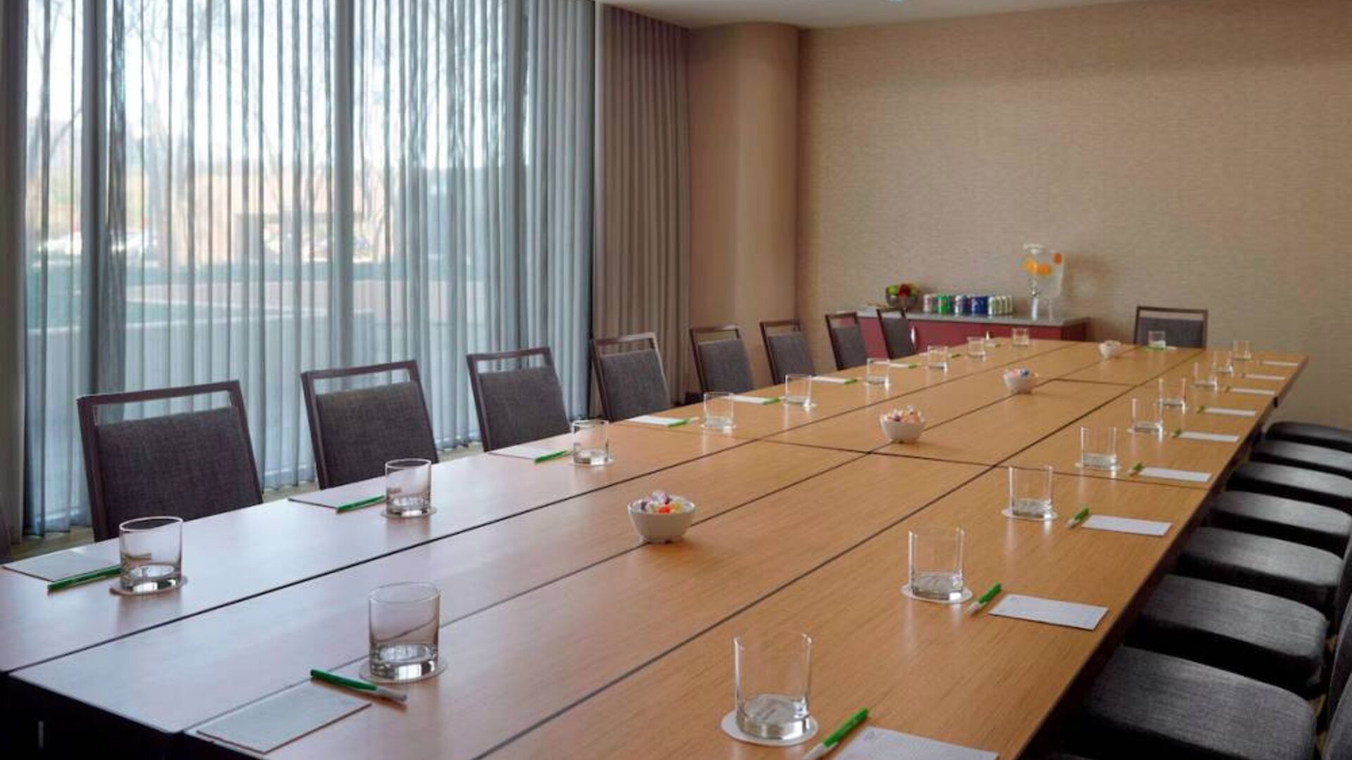 Hotel meeting room, with long wooden table, seating for over a dozen attendees, and large windows.