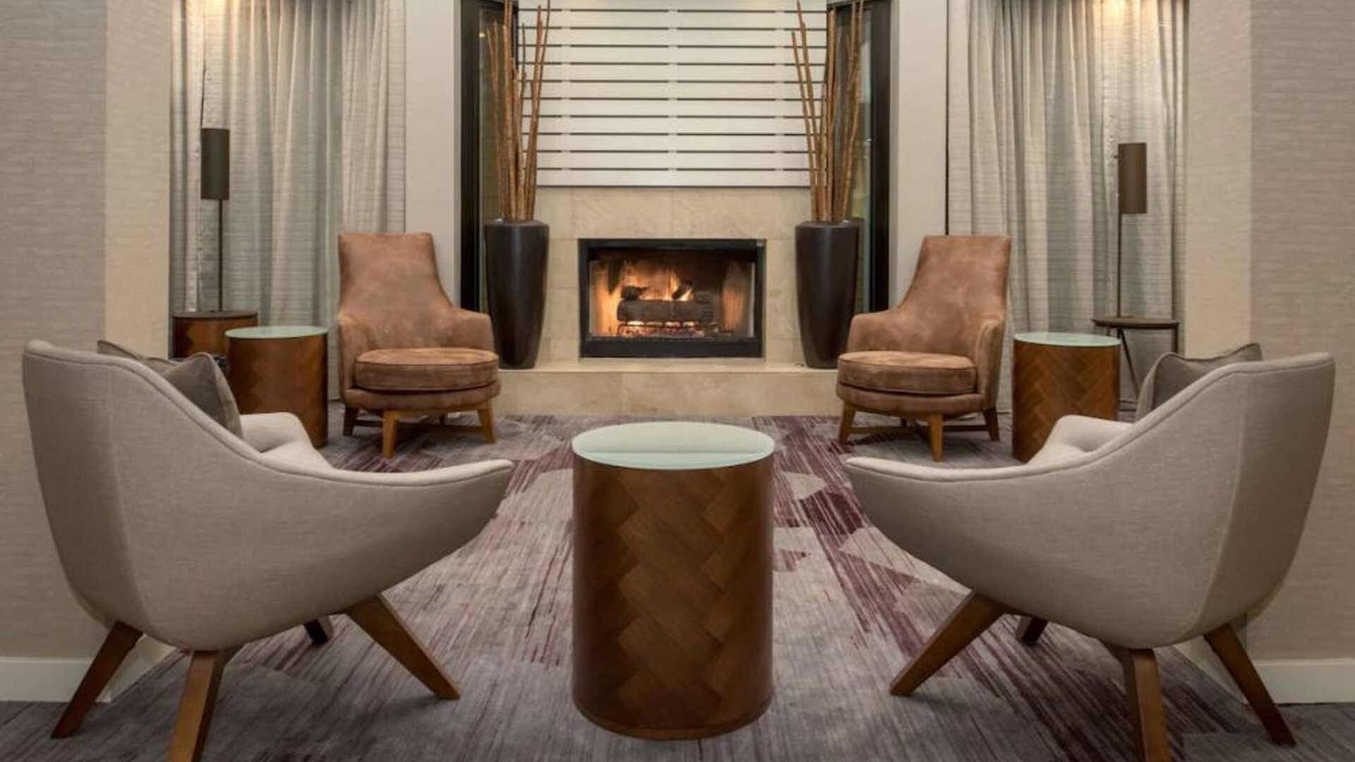 Sonesta Select Seattle Bellevue Redmond’s lobby includes coffee tables and comfy chairs close to a fireplace.