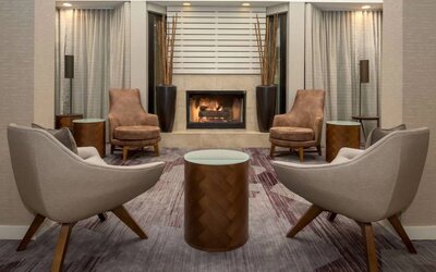 Sonesta Select Seattle Bellevue Redmond’s lobby includes coffee tables and comfy chairs close to a fireplace.