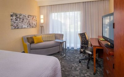 Double bed guest room in Sonesta Select Charlotte University Research Park, furnished with TV, chair, and sofa.