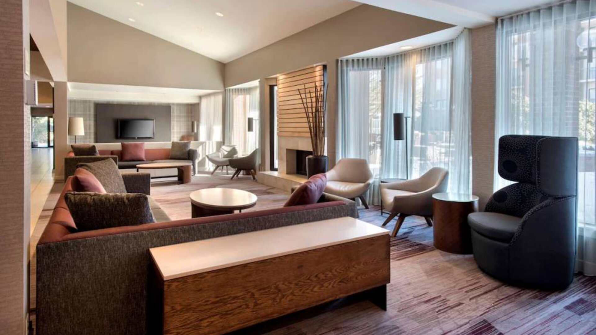 The lobby lounge in Sonesta Select Boston Milford includes chairs, sofas, and coffee tables, plus large windows.