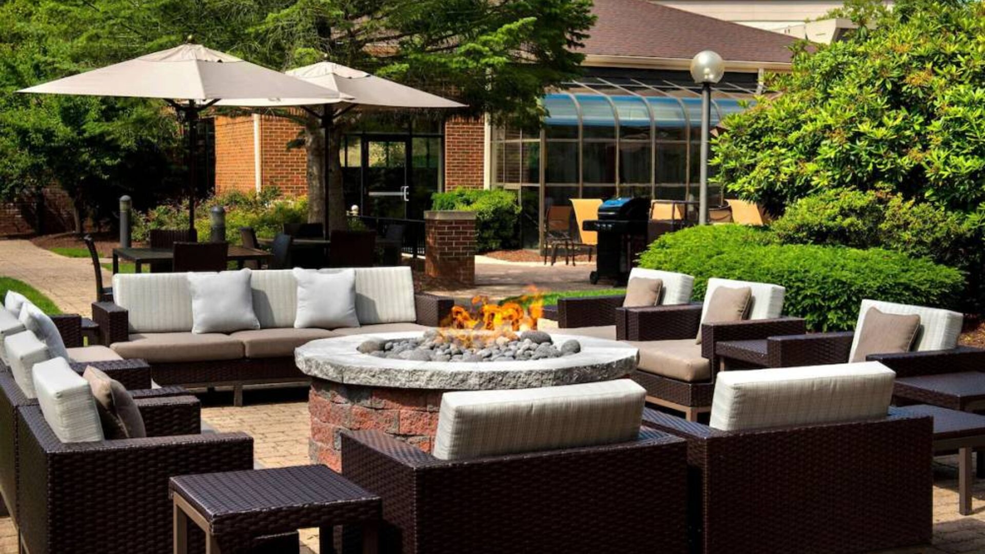 The hotel’s fire pit is surrounded by sofas and armchairs, and plenty of coffee tables, with pleasant greenery in the background.