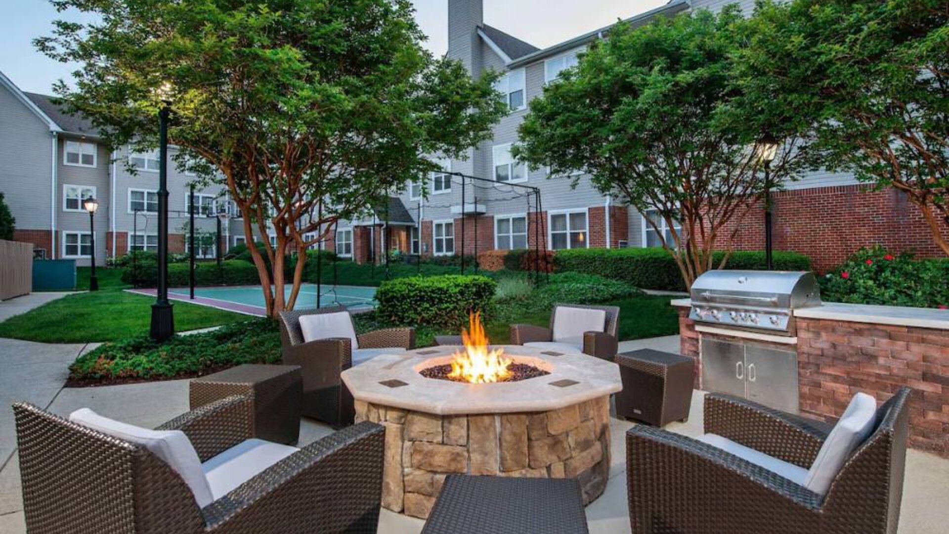 Sonesta ES Suites Baltimore BWI Airport’s fire pit is surrounded by armchairs and coffee tables, with a barbecue conveniently close.