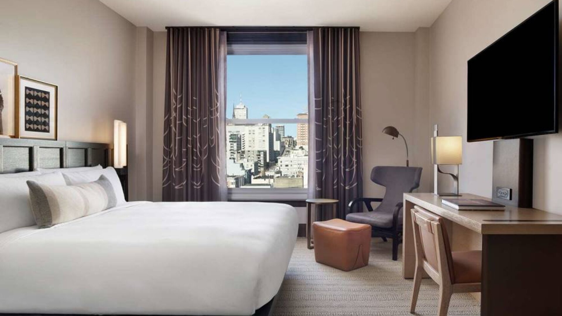 Double bed guest room in The Clift Royal Sonesta, with window, workspace desk/chair, and a large TV.