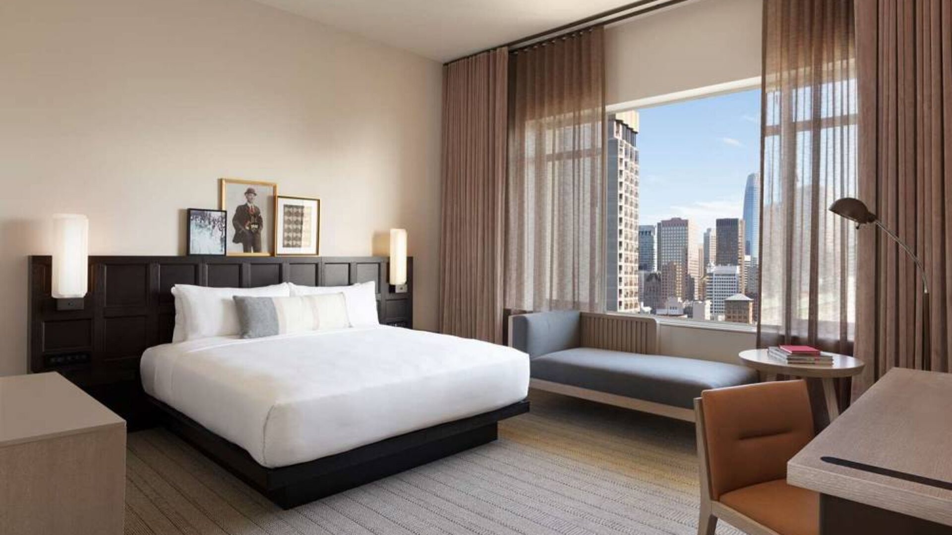 The Clift Royal Sonesta double bed guest room including sofa, window, and workspace desk and chair.