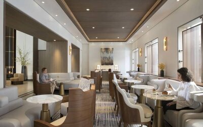 The hotel’s living room is furnished with comfortable seating and small tables, where guests can socialize, co-work, or have a drink.