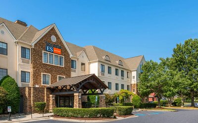 The hotel’s exterior has a pleasant abundance of greenery, including numerous trees, a covered entrance, and parking spaces.