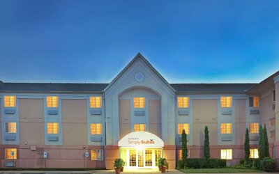 Sonesta Simply Suites Dallas Galleria’s exterior has well-kept greenery, including potted plants, clear signage, and parking spaces.