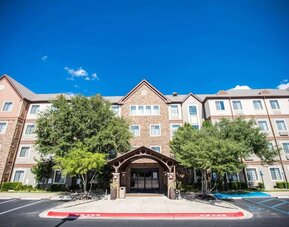 The hotel’s exterior has a covered entranceway flanked by trees, in addition to numerous parking spaces.