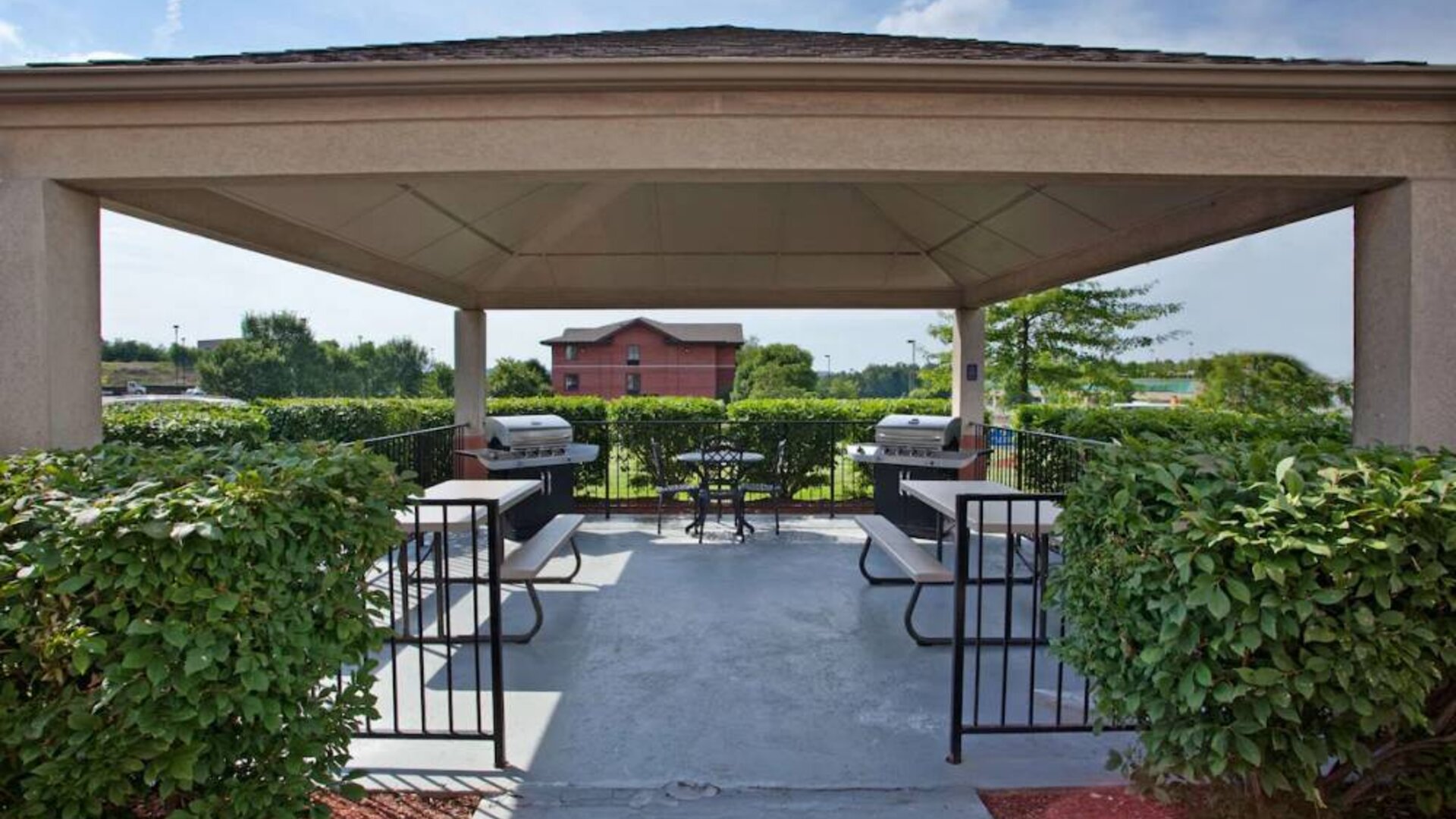 Sonesta Simply Suites Pittsburgh Airport’s gazebo features seating and tables outdoors and under cover, with two barbecues and a surrounding hedge.