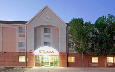 The hotel’s exterior has parking for guests on one side of the covered entrance, and trees to the other side.