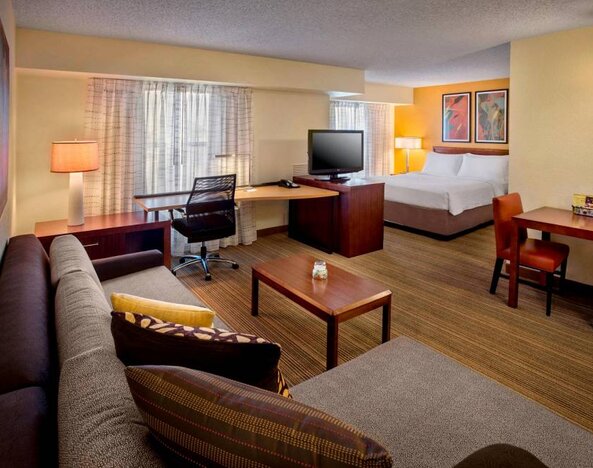 Double bed guest room in Sonesta ES Suites Birmingham Homewood, furnished with TV and sofa, plus workspace desk and chair.