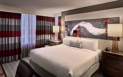 Double bed guest room in Sonesta Philadelphia Rittenhouse Square, including art on the wall, bedside lamps, and a large window.