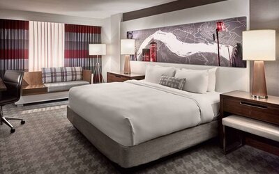 Double bed guest room in Sonesta Philadelphia Rittenhouse Square, including art on the wall, bedside lamps, chair, and a sofa.