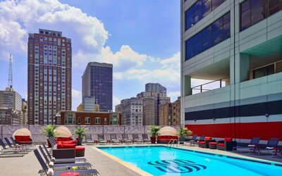 Sonesta Philadelphia Rittenhouse Square’s rooftop pool has sun loungers, armchairs, and potted plants by the side, addition to shaded seating.