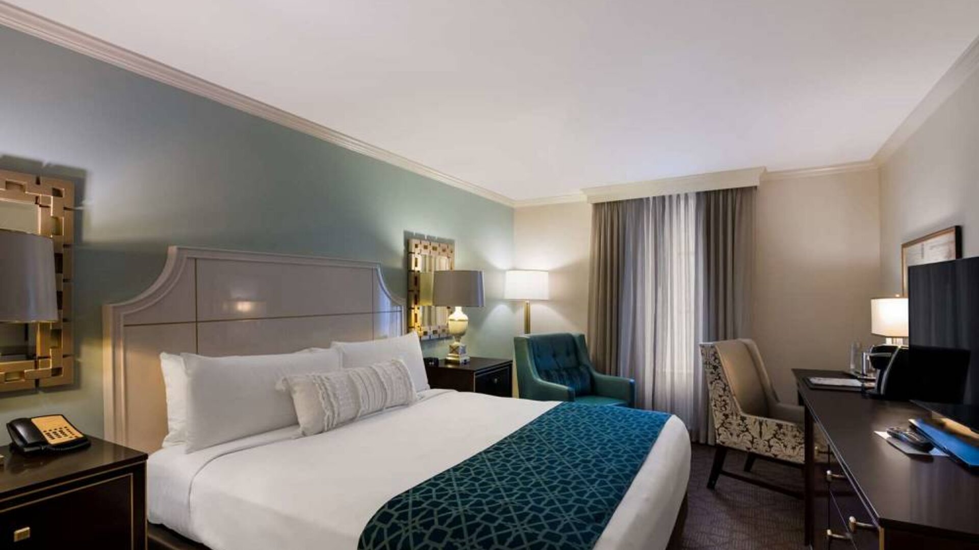 Double bed guest room in Royal Sonesta New Orleans, featuring television, armchair, and a workspace desk and chair.