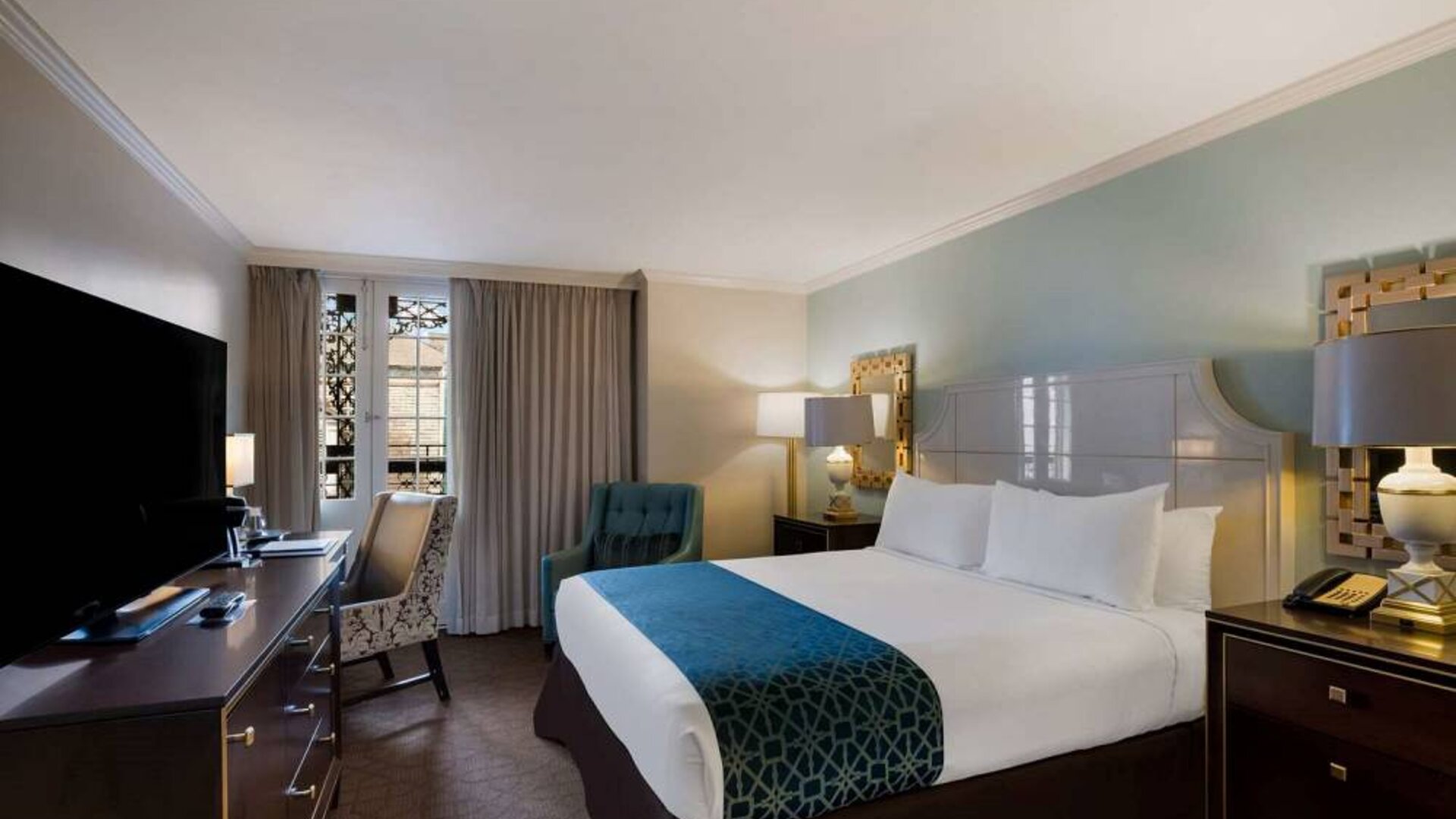 Royal Sonesta New Orleans double bed guest room, furnished with armchairs, desk, and a television.