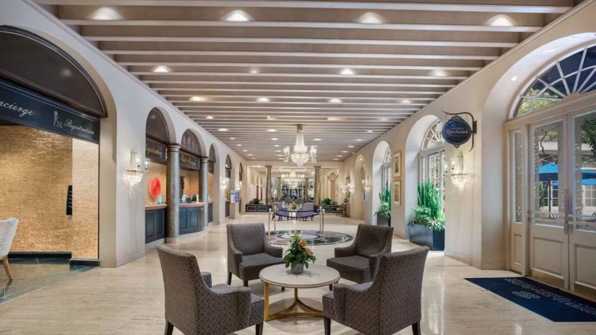 The hotel’s lobby lounge features armchairs, coffee tables, potted plants, and a spacious setting.