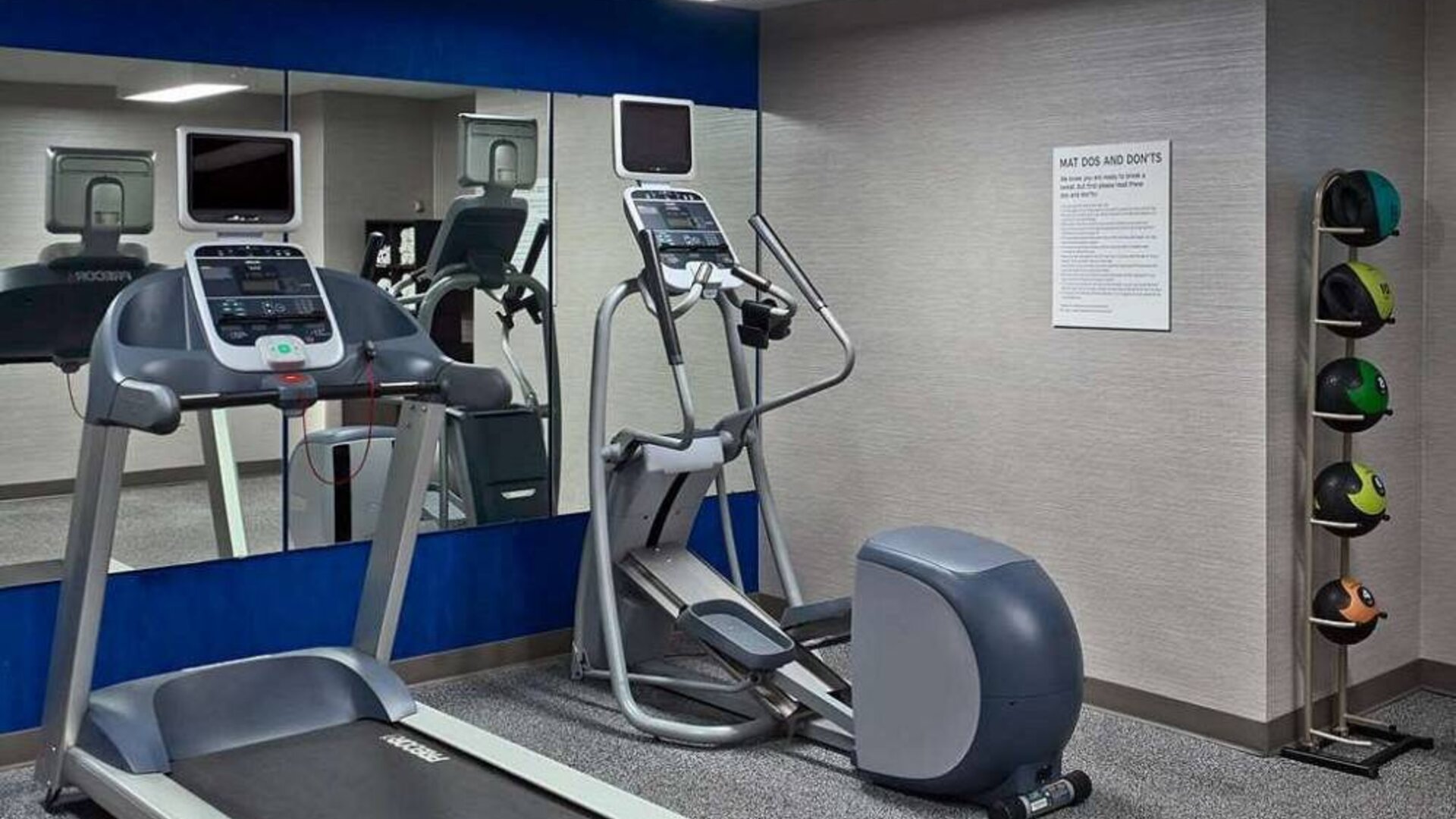 The hotel fitness center is equipped with towels, gym balls, and exercise machines such as an elliptical and a treadmill.