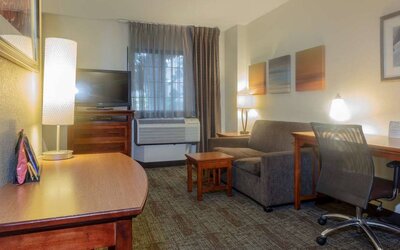 Guest room living area in Sonesta ES Suites Anaheim Resort Area, furnished with sofa and television, plus a workspace desk and chair.