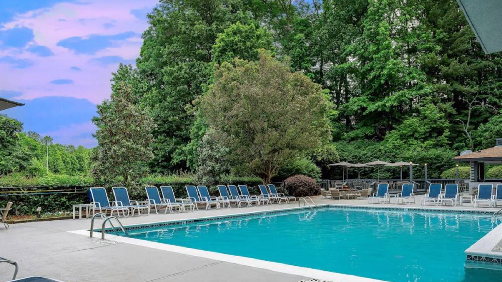 The outdoor pool at Sonesta Charlotte Executive Park has chairs by the side, is close to the fire pit, and connects directly to the indoor pool.