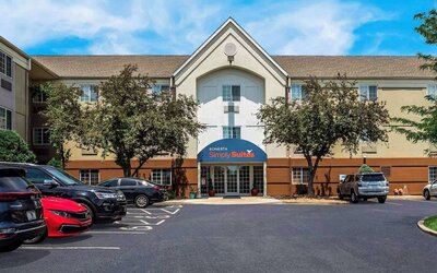 Sonesta Simply Suites St Louis Earth City’s exterior includes numerous parking spaces (including disabled spaces near the covered entrance) and trees.