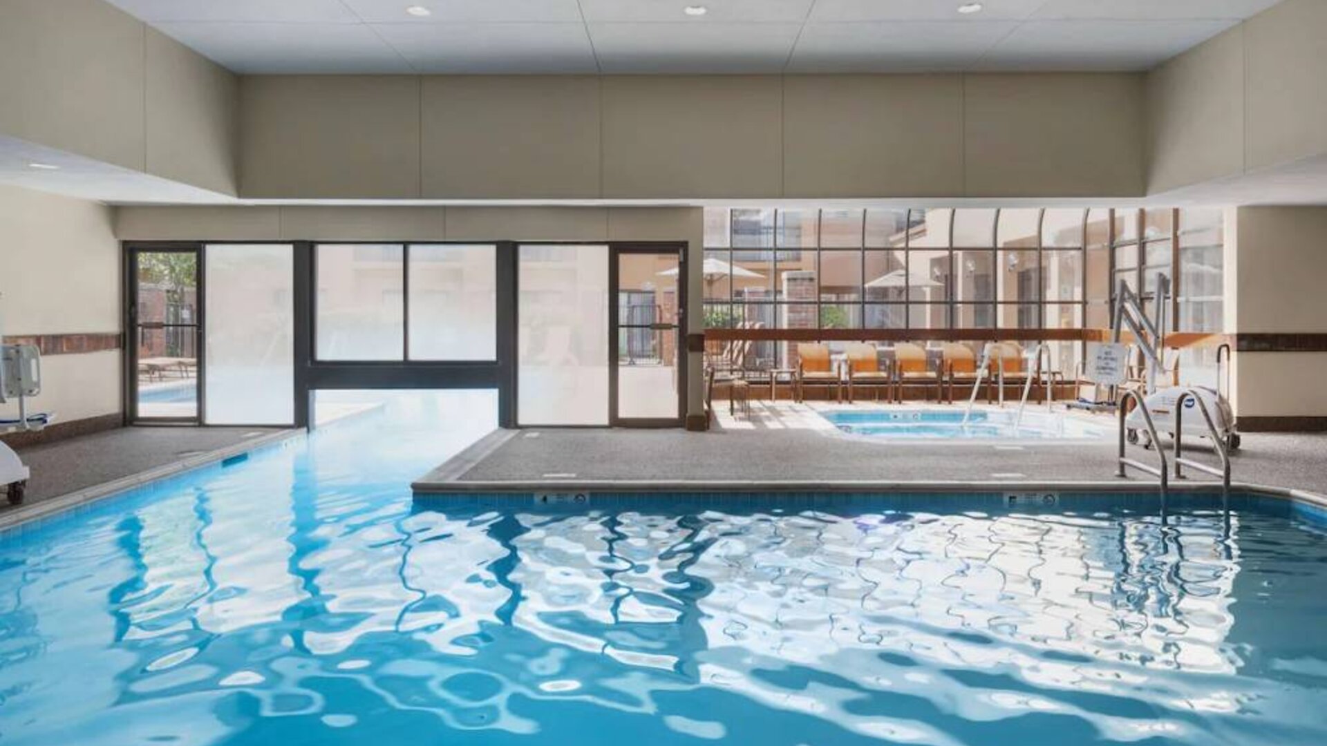 The hotel’s indoor pool has an adjacent hot tub and large windows, with a direct water link to the outdoor pool. 