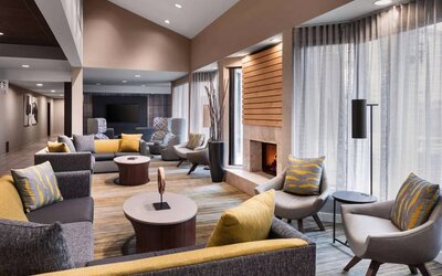 Sonesta Select Newport Middletown’s lobby lounge is furnished with comfy chairs and corners sofas, a fireplace and coffee tables, plus large windows.