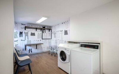 The hotel’s laundry room features a washer and drier, a pair of baskets, plus shelves and chairs.