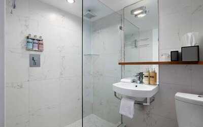 Guest bathroom in Nautilus by Sonesta, including shower, sink, mirror, and lavatory.