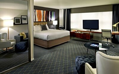 The Fifty Sonesta Select New York double bed guest room, including desk and chair, coffee table, window, and widescreen TV.