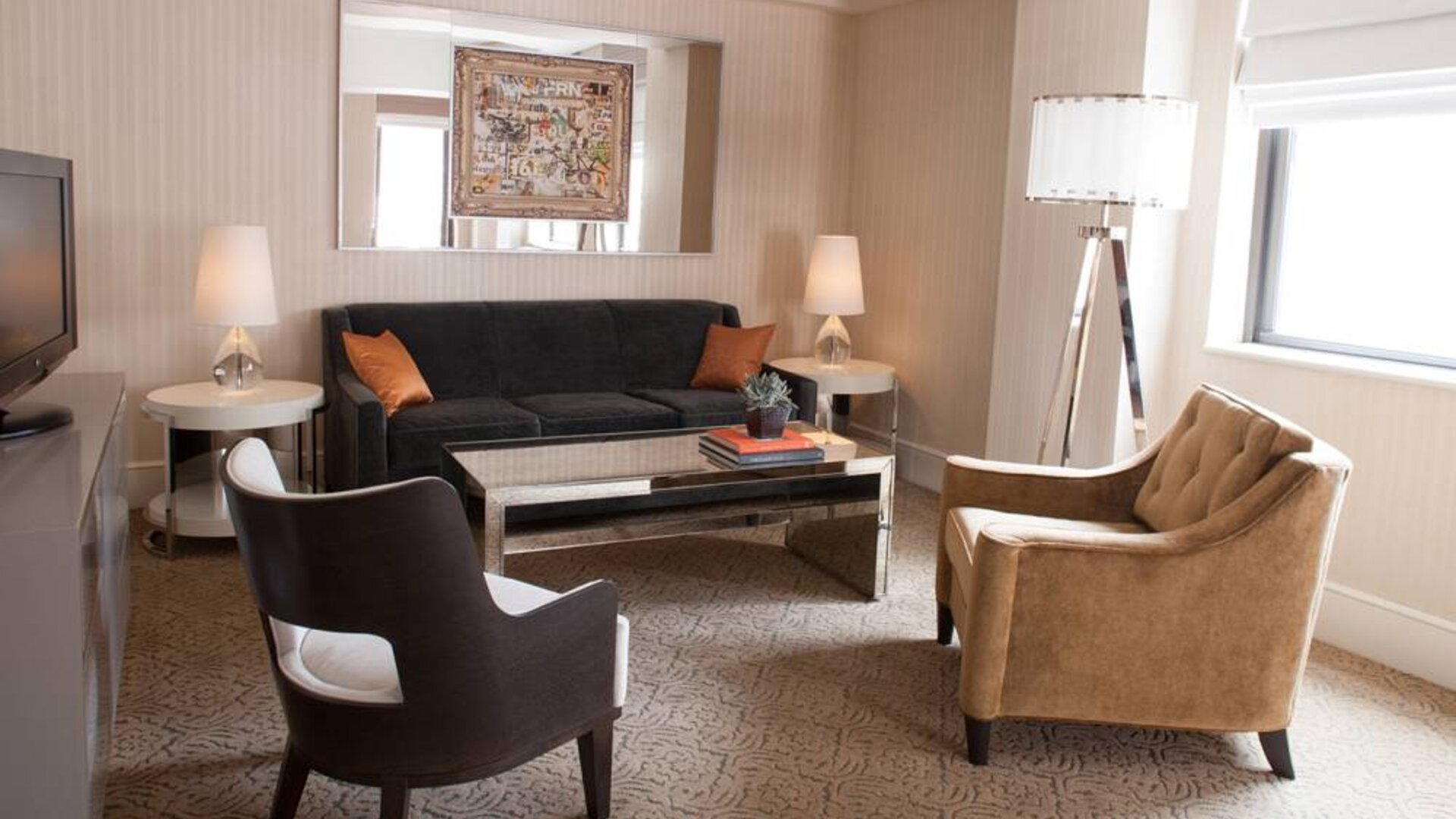 The Benjamin Royal Sonesta New York guest room living area, furnished with coffee table, chairs, TV, and sofa.