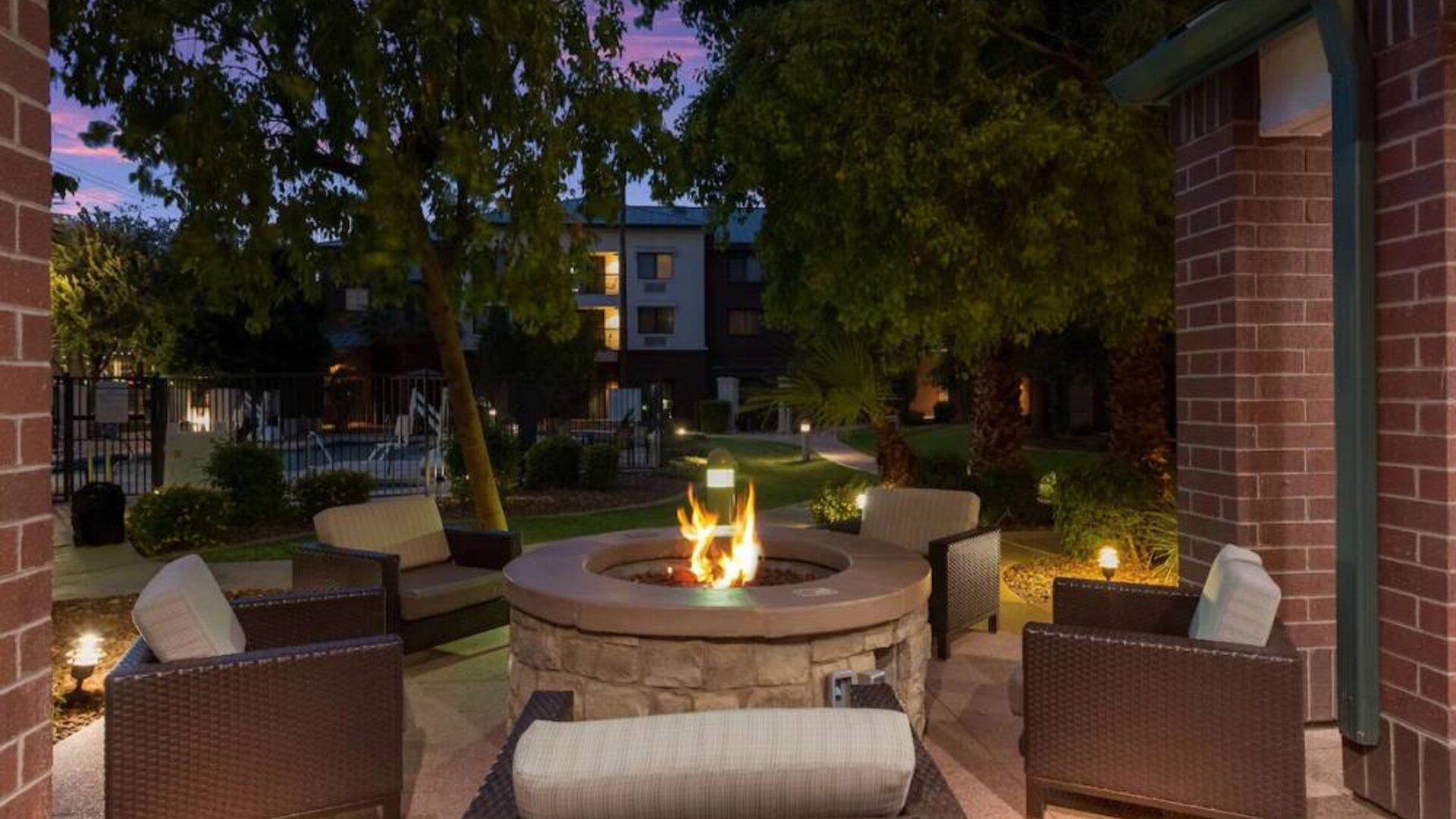 Sonesta Select Tempe Downtown’s fire pit is surrounded by armchairs, with trees nearby and the pool just steps away.