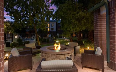 Sonesta Select Tempe Downtown’s fire pit is surrounded by armchairs, with trees nearby and the pool just steps away.
