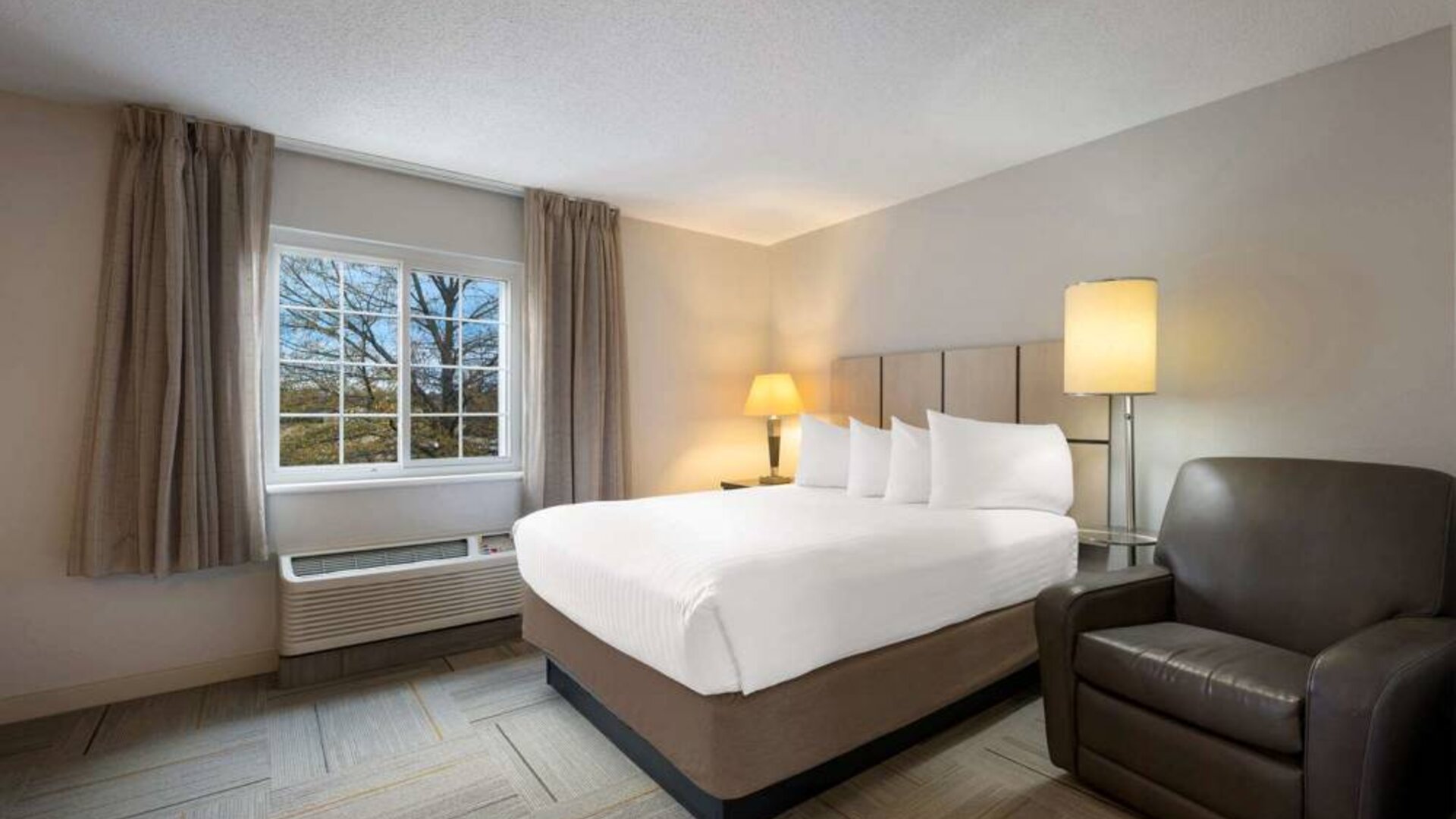 Double bed guest room in Sonesta Simply Suites Huntsville Research Park, including a window and armchair.