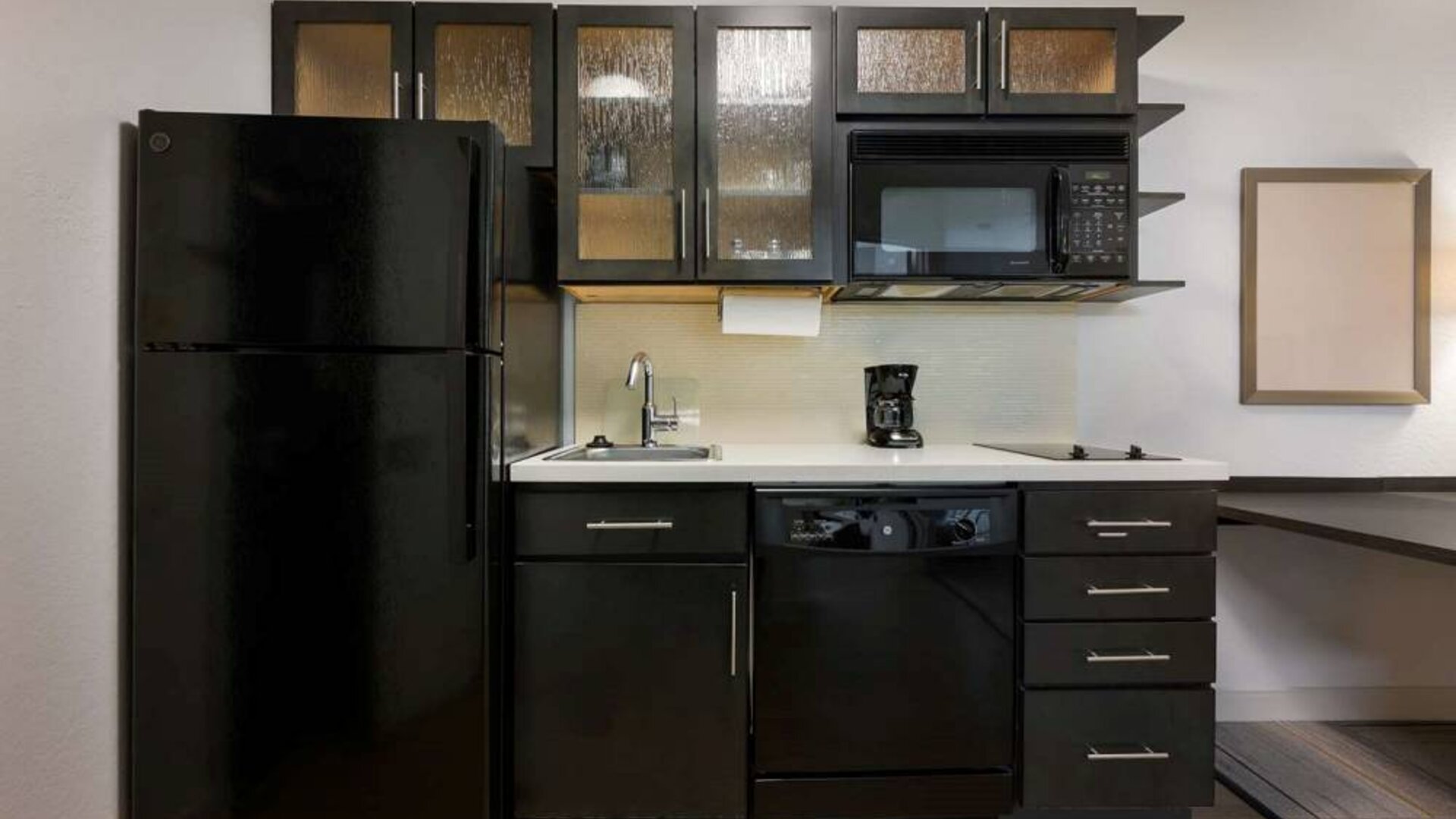 Sonesta Simply Suites Huntsville Research Park guest room kitchen, with fridge-freezer, oven, hob, and microwave.