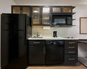 Sonesta Simply Suites Huntsville Research Park guest room kitchen, with fridge-freezer, oven, hob, and microwave.