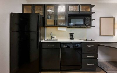 Sonesta Simply Suites Huntsville Research Park guest room kitchen, with fridge-freezer, oven, hob, and microwave.