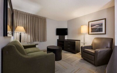 Guest room lounge in Sonesta Simply Suites Huntsville Research Park, furnished with sofa, armchair, coffee table, and window.