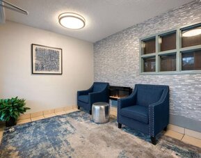 The hotel lobby has a pair of blue armchairs with a fireplace and coffee between them, and a potted plant in the corner.
