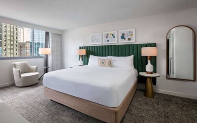 Royal Sonesta Chicago Downtown double bed guest room, including mirror and art on the wall, armchair, and views of the city.