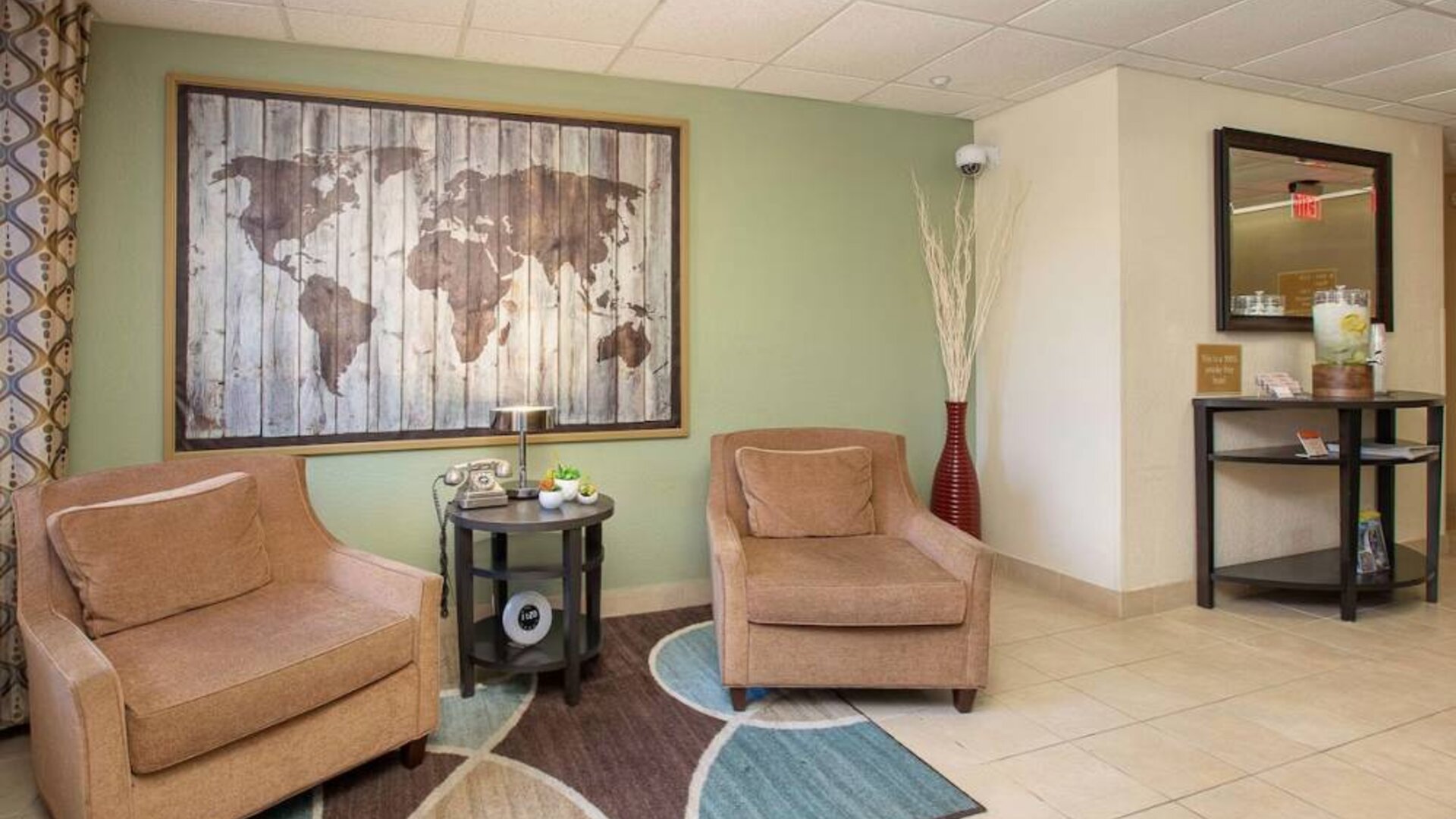 The hotel’s lobby is furnished with a pair of armchairs, a coffee table, and an artistic map of the world on the wall.