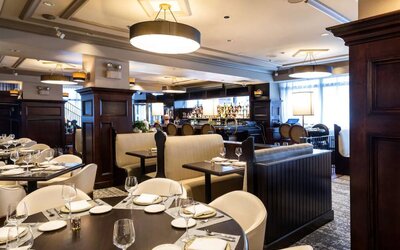 The hotel’s restaurant offers both table and booth seating, with a mix of white seats and dark wood tables, plus a bar.