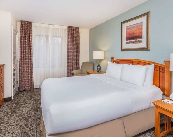 Sonesta ES Suites Atlanta - Perimeter Center double bed guest room, featuring TV, armchair, and window.
