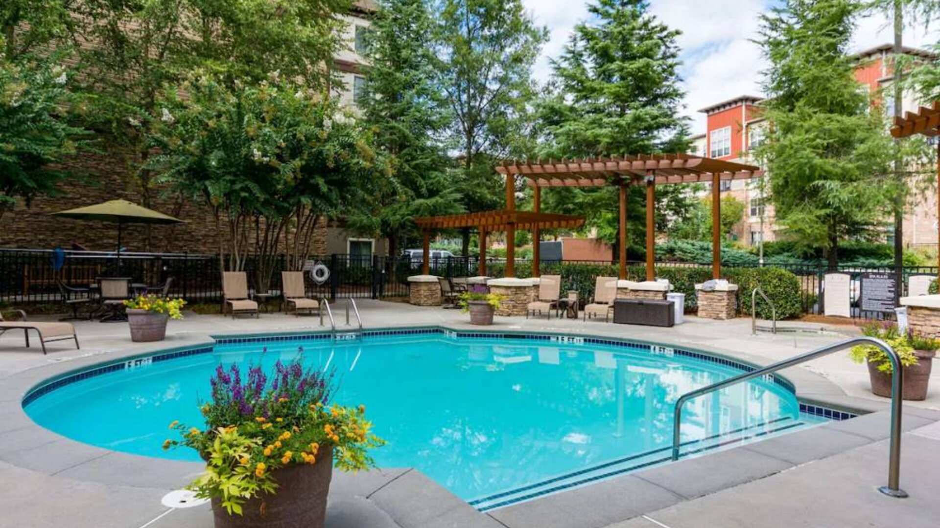 Sonesta ES Suites Atlanta - Perimeter Center’s round outdoor pool has potted plants and sun loungers nearby, with tables and chairs close at hand.