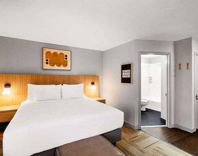 Double bed guest room in Sonesta Simply Suites Austin South, featuring art on the wall and an ensuite bathroom.