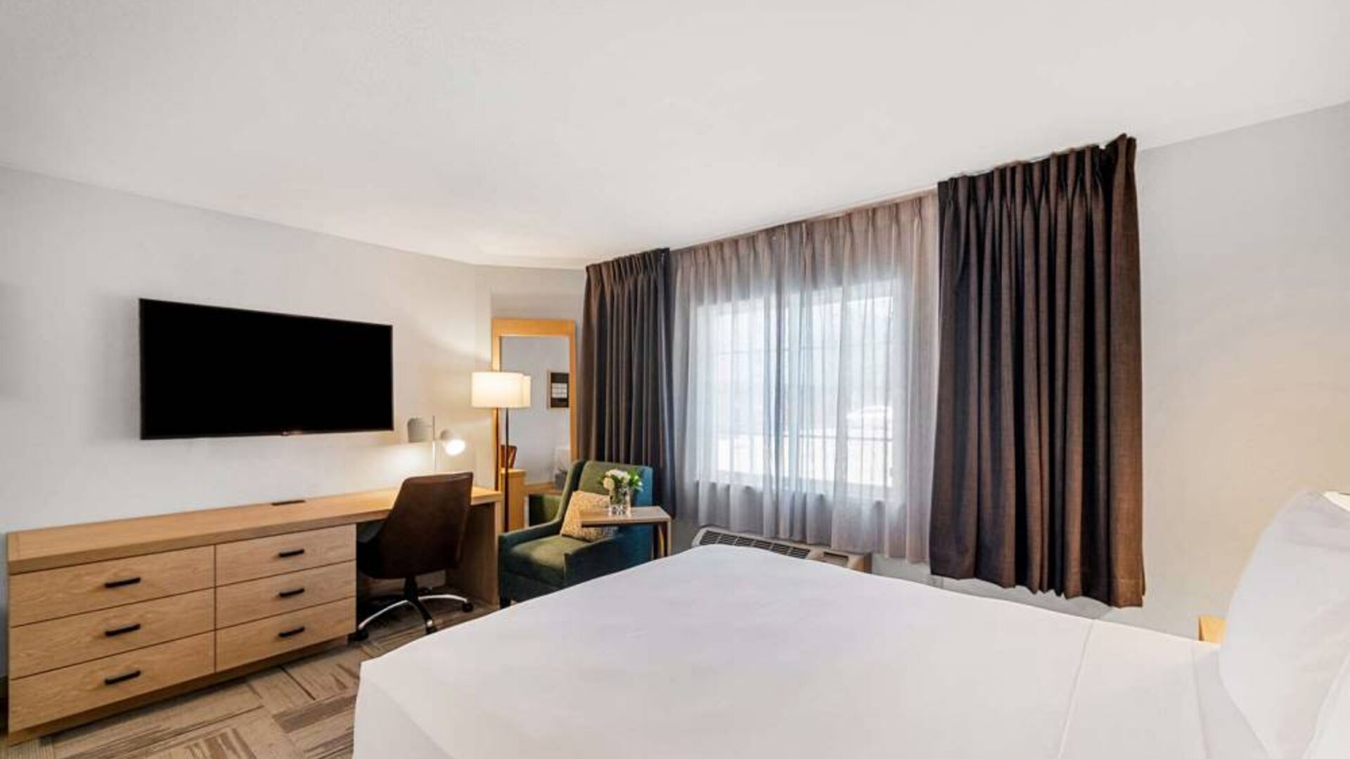 Sonesta Simply Suites Austin South double bed guest room, featuring window and TV, plus a workspace desk, chair, and lamp.